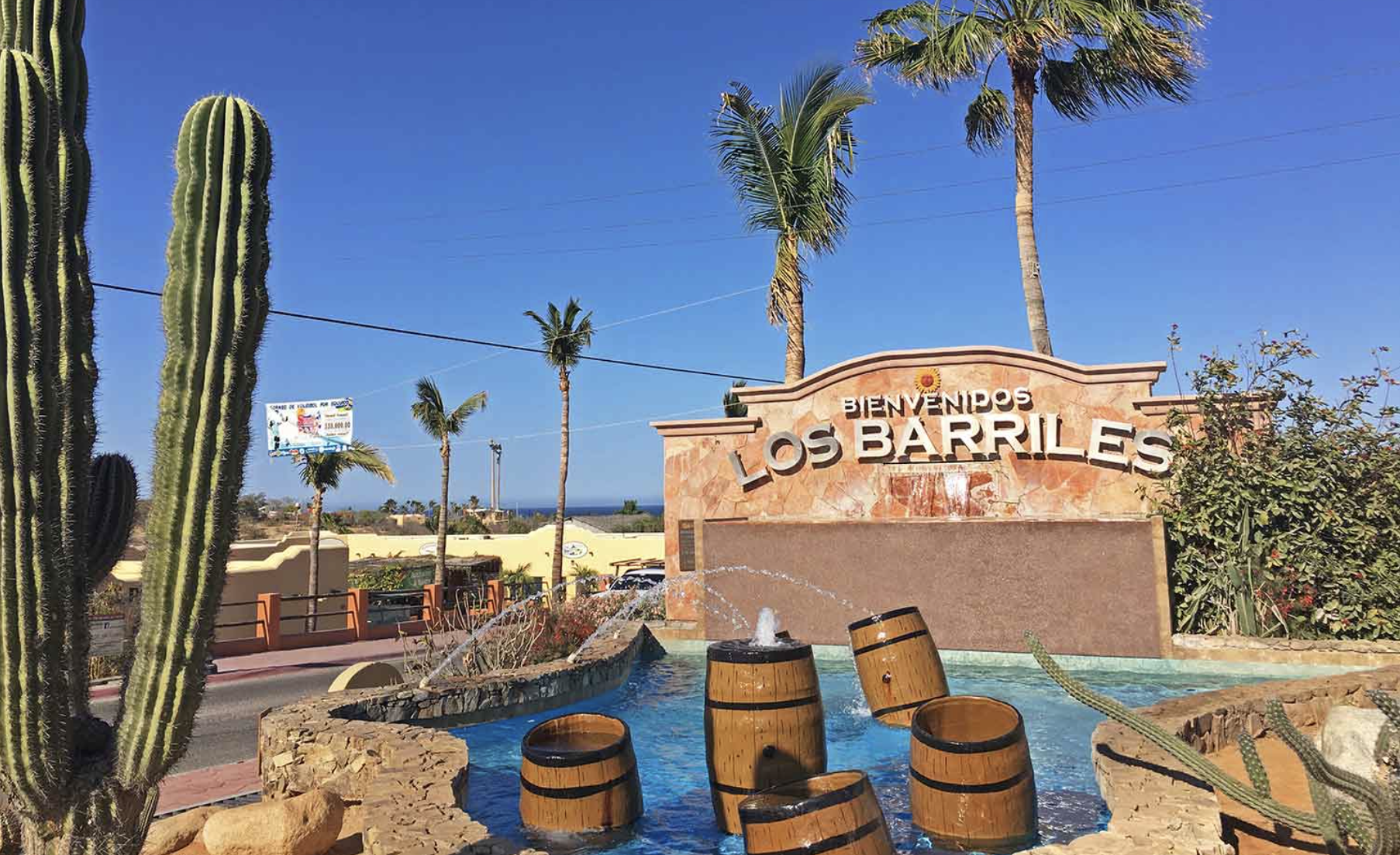 Welcome to Los Barriles sign surrounded by cacti and palm trees